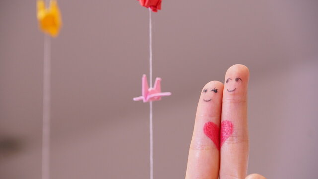 Finger drawing, family is holding a heart, love couple with drawing finger, paper crane background
