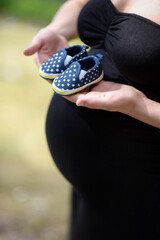 Pregnant woman holding baby shoes - 361446885