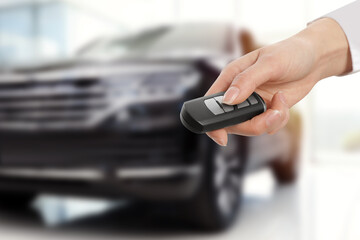 Woman with key near new automobile indoors, closeup