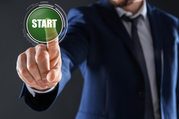 Man pointing at start icon on dark background, closeup