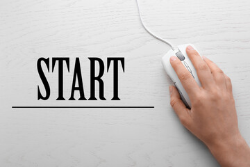 Woman with computer mouse and word START on wooden background, top view