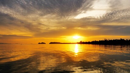 Sunset time above the ocean, reflective water surface in slow motion during the golden hour