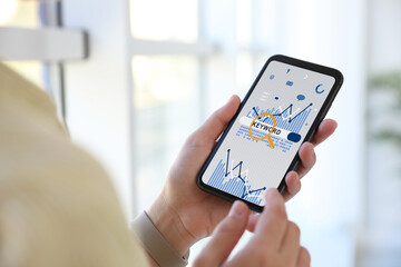 Woman with smartphone searching for keywords indoors, closeup