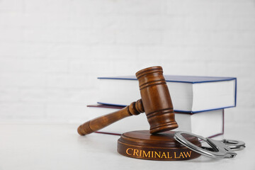 Gavel, handcuffs and books on table against white background. Criminal law concept