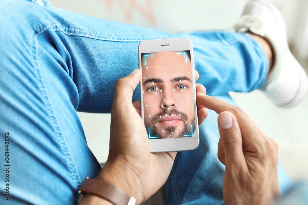 Poster man using smartphone with facial recognition system indoors, closeup. biometric verification