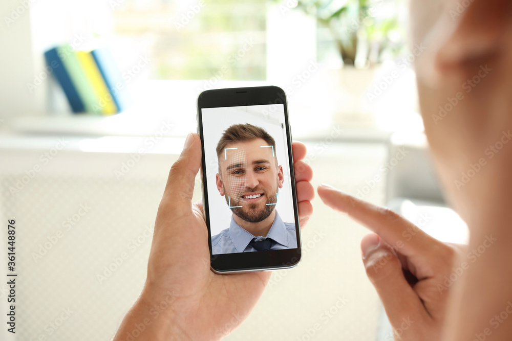 Poster man using smartphone with facial recognition system indoors, closeup. biometric verification