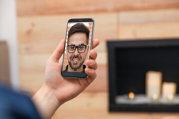 Man using smartphone with facial recognition system indoors, closeup. Biometric verification