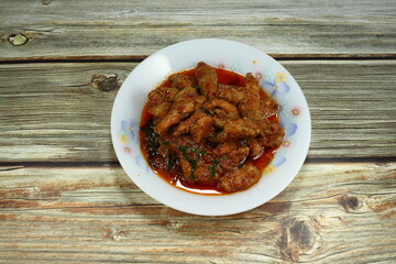 Fried spicy chopped pork with Thai red chilly curry paste, fresh basil and coconut milk on the plate. Famous traditional hot and spicy menu in Asia restaurant. 