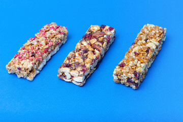 Three protein bars with cereals isolated on blue background