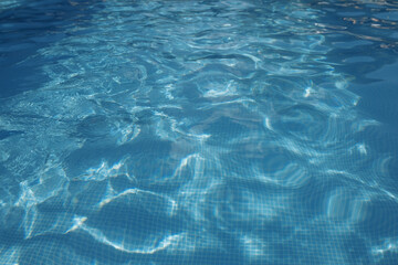 Photo of water in swimming pool, surface of blue pool, ripple vacuity in pool, sun reflection in basin, clear light blue pool water, top view of backwash in basin, rippled aqua detail background