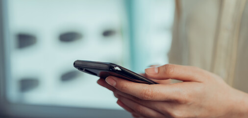 Closeup of young woman hand holding smartphone and chatting with friends at social network.