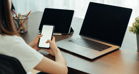 Woman using digital laptop and tablet with smartphone on the table in house. Blank screen for advertising.