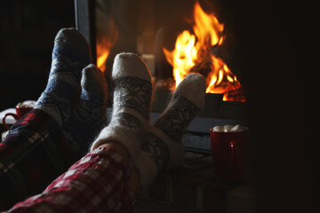 Couple in pajamas resting near fireplace indoors, closeup. Winter vacation