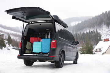 Black car with luggage in trunk on snowy road. Winter vacation