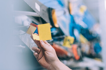 The buyer in the hardware store selects the goods. A man holds a price tag in his hand.