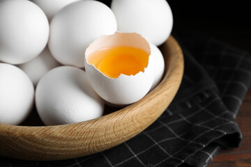 Many fresh raw chicken eggs in bowl on table, closeup