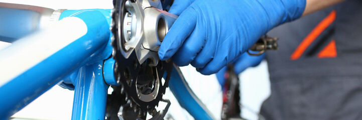 Male bicycle master inspects bicycle mechanism. After-sales service for bicycles. Preparation for new bike season. Avoid unplanned and unexpected damage. Replacing connecting rod system