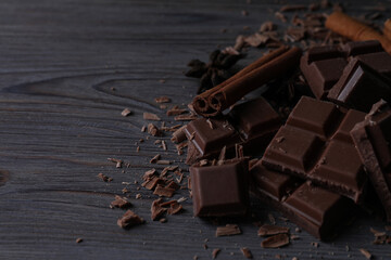 Delicious milk chocolate and cinnamon on wooden table. Space for text