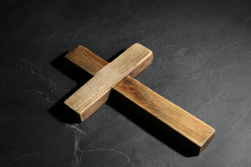 Wooden Christian cross on black slate table. Religion concept