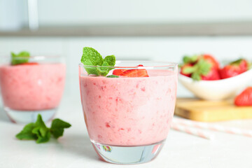 Tasty strawberry smoothie with mint in glass on light grey table