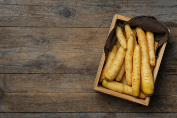 Raw white carrots in crate on wooden table, top view. Space for text