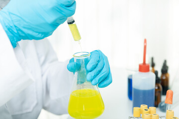 Researcher or scientists loads liquid sample into beaker in laboratory. Researchers are developing vaccines and medicine to treat the COVID-19 virus.