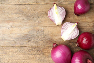 Ripe red onion bulbs on wooden table, flat lay. Space for text