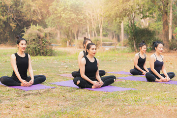 Group of asian women doing yoga beside the lake in outdoor park.