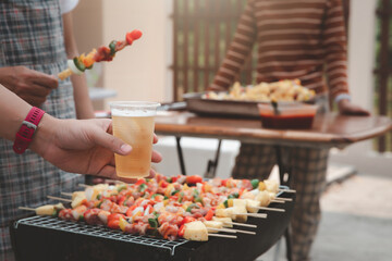 Young men cheers for a drink at a BBQ party between friends. Food, drink, people and family time concept.