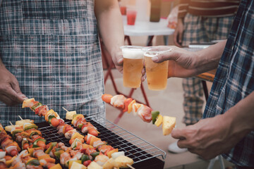 Young men cheers for a drink at a BBQ party between friends. Food, drink, people and family time concept.