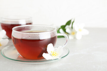 Cup of tea and fresh jasmine flower on light grey marble table