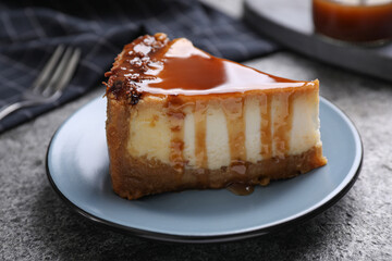 Piece of delicious cake with caramel served on grey table