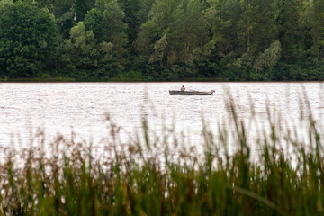 A fisherman on a boat on the Dnieper River in Kiev, Ukraine, between reeds and the forest