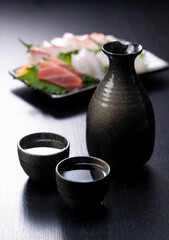 Obraz na płótnie Canvas Sake and sashimi on a black background