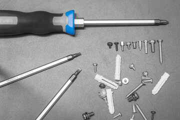 Several screwdriver and screws set are spread on the black surface.
