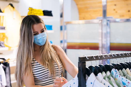 Young Woman in mask shopping at a clothing store in the coronavirus pandemic