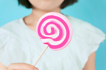 Girl eating lollipop candy.  渦巻状のペロペロキャンディーを食べる女の子