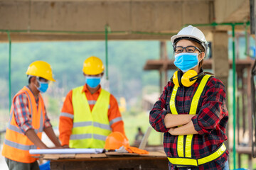 Team engineers and architect having wearing protective masks to prevent dust and covid 19 disease during the inspection in construction site.