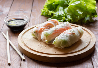 Spring rolls Vietnamese shrimp and funchoza on a wooden Board with chopsticks and soy sauce.