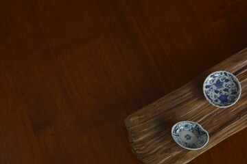 picture plate. put a Japanese traditional ceramic “ imari ware ” on a driftwood board.  Top view photo of expensive antique walnut table is made in England.  wooden background with copy space.