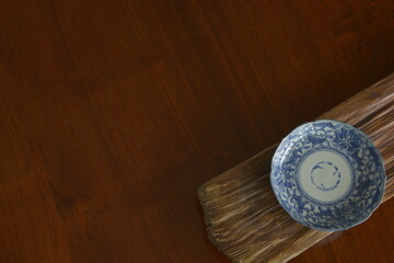 picture plate. put a Japanese traditional  ceramic “ imari ware ” on a driftwood board.  Top view photo of expensive antique walnut table is made in England.  wooden background with copy space.