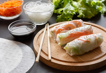 Spring rolls Vietnamese shrimp and funchoza on a wooden Board with chopsticks and soy sauce.