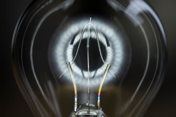 Close up of the filament of a light bulb with a halo against black background