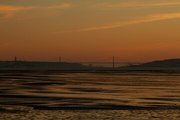 Low light image taken at sunset on the banks of Tagus River that lies between Almada and Lisbon. It features silhouettes of both cities, the 25 de abril suspension bridge and Christ the king monument.