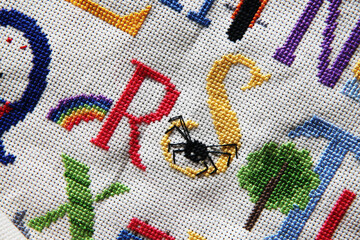 Closeup detail of cross stitch also known as needle craft, includes animals and alphabet