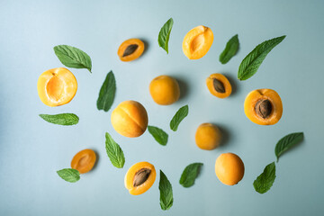 Ripe apricot slices and mint leaves are flying above blue surface
Flat lay with tasty apricots on mint background