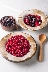 frozen cranberries and chokeberries in clay dishes on a light background