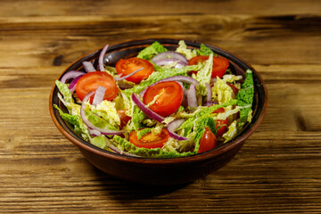 Healthy salad with savoy cabbage, cherry tomato, red onion and olive oil on wooden table