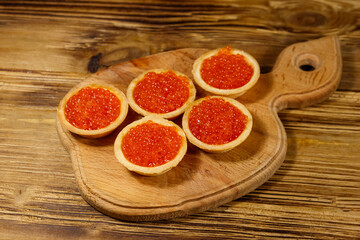 Tartlets with red caviar on a wooden table
