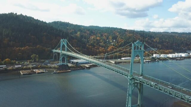 Beautiful 4k aerial footage of the St. Johns Bridge in Portland - Oregon while autumn with colorful yellow and orange forest in the background.